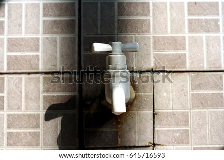 Photo of a plastic water faucet in a sink with ceramic tiles