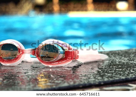 Photo of a colorful pair of swimming goggles beside a swimming pool