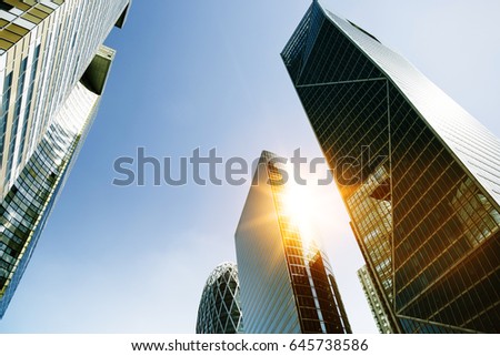 Skyscraper glass facades on a bright sunny day with sunbeams in the blue sky. Modern buildings in Paris business district La Defense. Economy, finances, business activity concept. Bottom up view