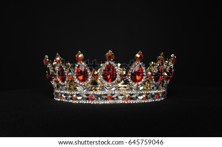 still life portrait of a golden and red crown against a black background. Royalty-Free Stock Photo #645759046