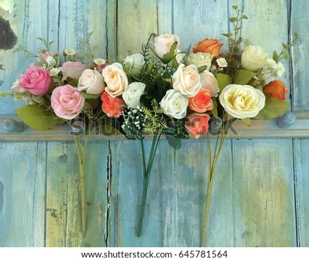Beautiful artificial flowers on pastel wood background