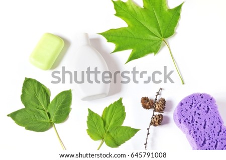 Organic bath products with green leaves on a white background. Soap, shampoo and purple sponge. Hair care concept. Flat lay beauty photography