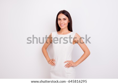 Portrait of slim cute girl in white smart clothes with her hands on the hips. She is successful and beautiful. Behind is a snow white background Royalty-Free Stock Photo #645816295
