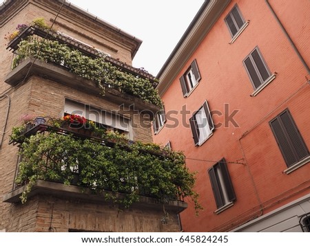 Ferrara, Italy. Pink facade with windows and house with flowery balconies.