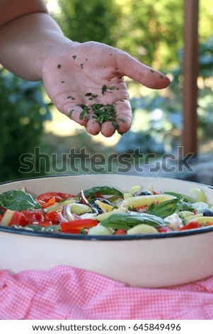 Putting parsley in a bowl of Greek salad. Selective focus. 