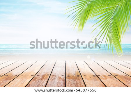 Empty wooden table and palm leaves with party on beach blurred background. Concept Summer, Beach, Sea, Relax, Party. 