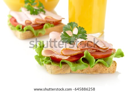 Toasts with cold cuts for breakfast with orange juice on white background
