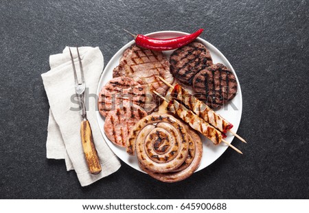 Meat barbecue party. Meat grilled on a plate, basil leaves, tomatoes and fork for meat