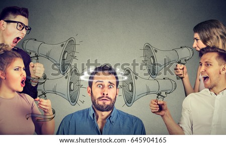 Group of people screaming in megaphones at scared guy  Royalty-Free Stock Photo #645904165