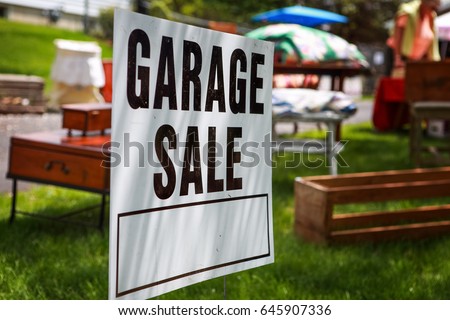Garage sale sign on the shady lawn of a suburban home, shallow focus in center of sign