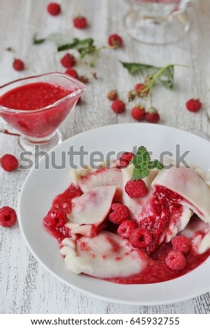 sweet dumplings, called varenyky or pierogi, with raspberries and berry sauce on a light background