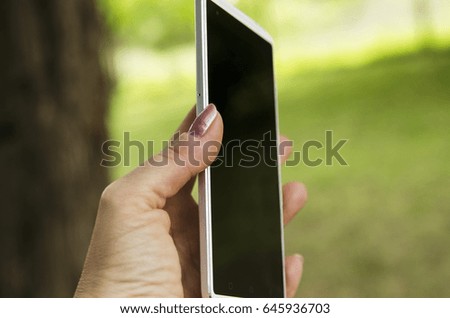 Cell phone profile close up in woman hand outdoor. Nature blur  background