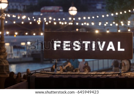 Festival sign with blurred string lights in the background