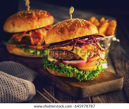 Delicious homemade hamburger on wooden background. Rustic style. Retro toned.