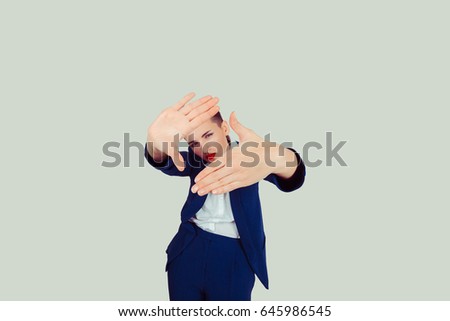 Woman making a frame with her huge big hands looking through it thoughtful thinking at the results isolated light green background. 