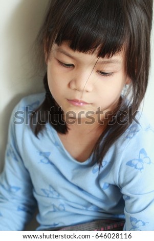 Little Asian girl wearing Thai traditional dress sitting the wooden terrace,Portrait of Thai little girl mixed and match sarong and brand name long sleeve tee.
