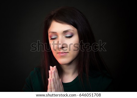 Young woman praying, Studio shot on dark background