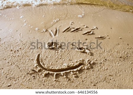Funny smile face drawn on wet sand near sea