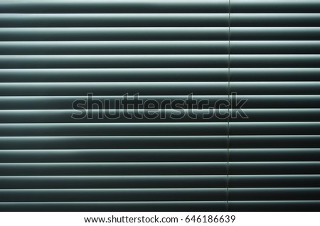 Closed venetian blinds or shutters background. Daylight coming through closed metallic blinds.Nighttime privacy.