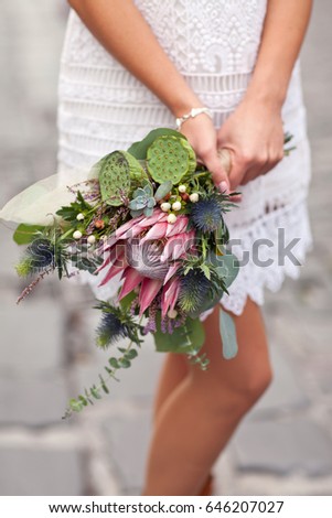 Photo of a girl with flowers on a stone pavement.