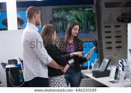 Young couple in consumer electronics store looking at latest laptop, television,mobile and photo camera