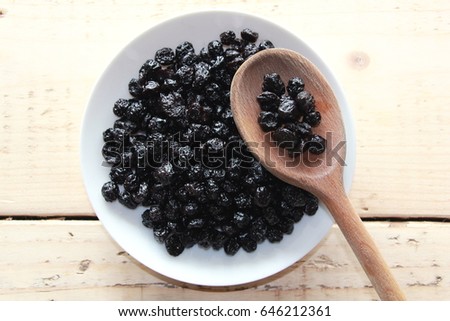 Dried blueberries on a white plate with a wooden spoon Royalty-Free Stock Photo #646212361