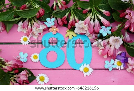 Number seventy   amongst spring flowers on bright pink wooden painted boards, a birthday card image for an seventieth celebration  