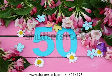 Number fifty  amongst spring flowers on bright pink wooden painted boards, a birthday card image for an fiftieth celebration  