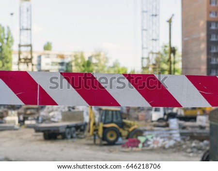 Red-white emergency tape on construction site background. Do not cross tape barrier. Cordon tape.