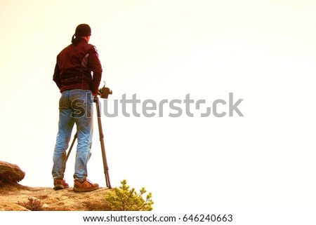 Silhouette of a landscape photographer on peak above misty valley. Photograph silhouette