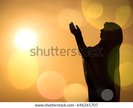 Silhouette Muslim Arabic woman praying with her hands up