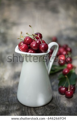 Moody picture of fresh and juicy cherries in a white vintage milk churn