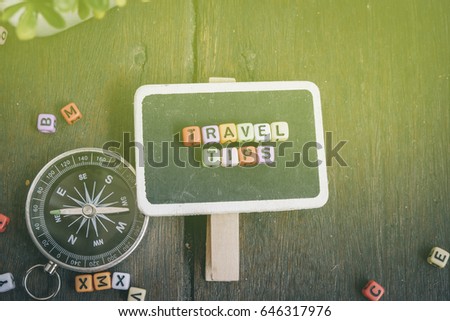 Vacation and holiday concept, TRAVEL TIPS word block on signage and compass over wooden background with light effect