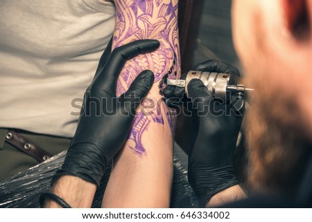 Focus on arms of male master making tattoo with special machine in apartment. Close up