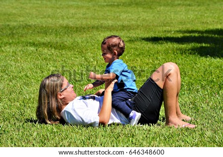 Mother and son playing on grass on sunny day.