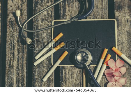 top lay view, stethoscope, cigarette, signage and flower on wooden background ideal for health concept
