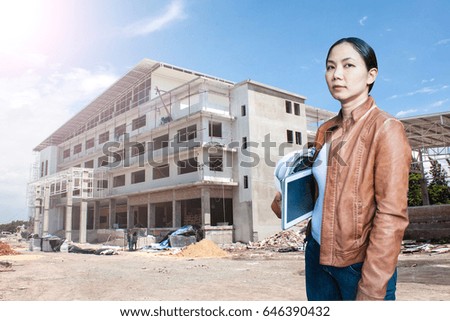 woman contractor engineer holding white helmet and tablet with site under construction background