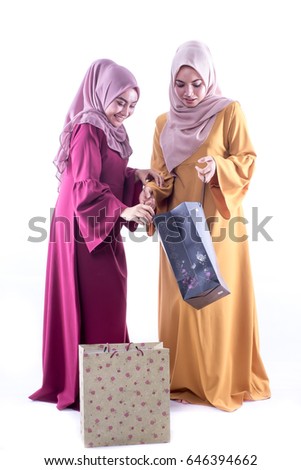 Young Muslim woman in head scarf with modern clothes with shopping bags for hari raya aidilfiti, isolated on white. 