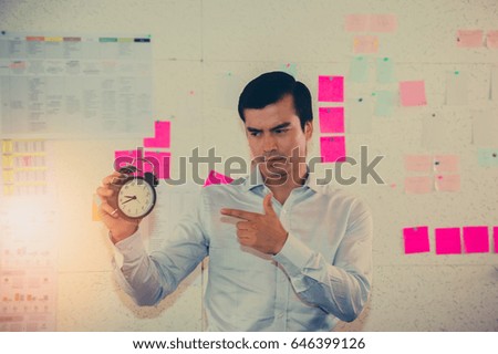 Young businessman  with a clock 
in the background office.