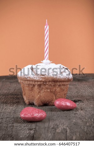 Homemade cake with candle and sugar powder on the old wooden table opposite bright orange background. Selective focus. Toned.