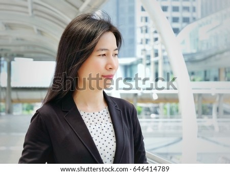 Beautiful young asian business woman standing in front of office building in business area.