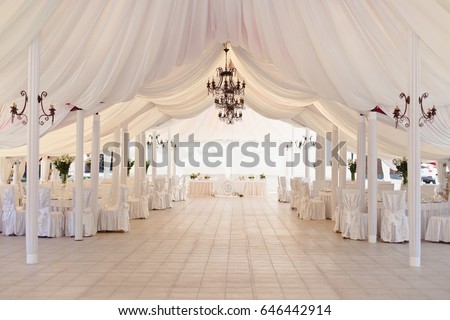 Marquee for the celebration of the wedding. Beautiful white interior with white draperies Royalty-Free Stock Photo #646442914