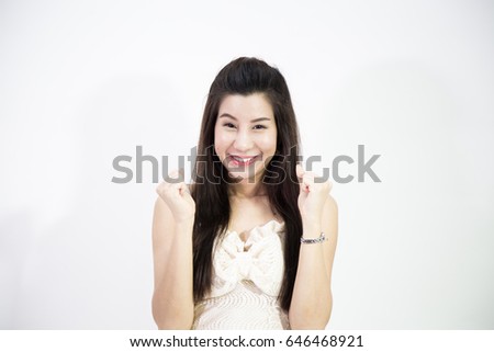 Happy beautiful young asian woman is keeping hands in fists and smiling, isolated on white background