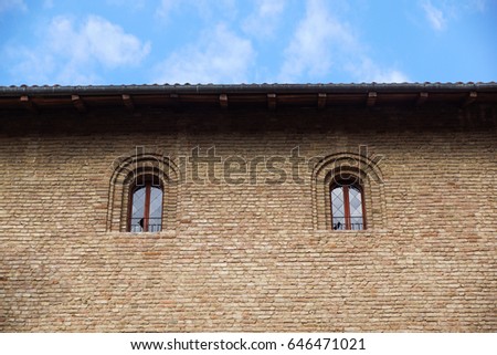 Castle window in a medieval style. Double arched window on a facade of medieval wall. Biforium - ancient window with column, old architecture element of Roman and Gothic styles.
