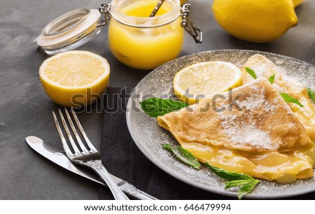 Fresh homemade crepes with lemon curd on gray concrete background. Selective focus.