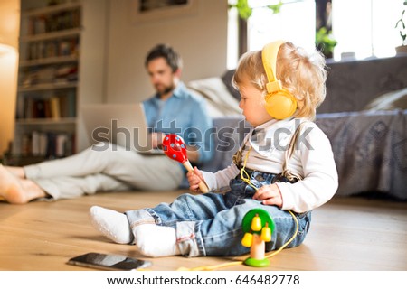 Father and son with smartphone, earphones and laptop.