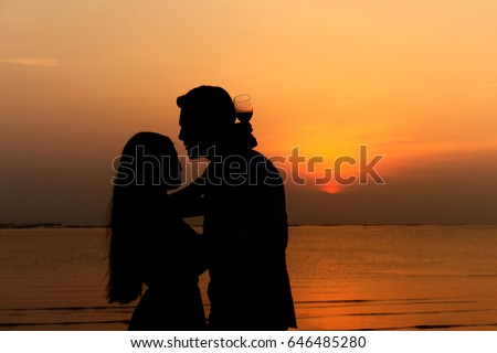 Front view of a  body of a couple silhouette on the beach at sunset in summer