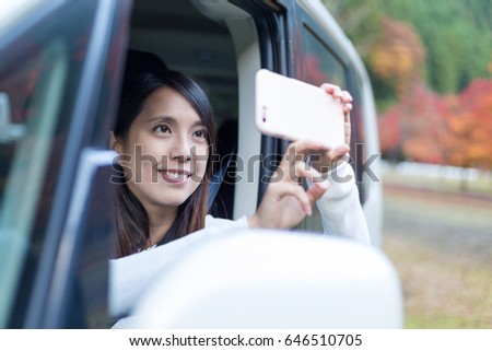 Woman taking photo with cellphone inside a car