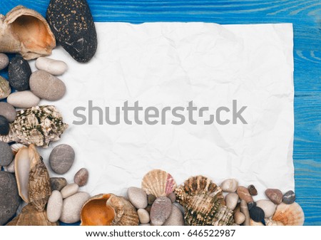 Seashell, pebbles and blank note paper on blue wooden background.