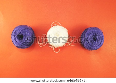 Top view of a background for a seamstress. Hanks thread, red fur, tissue samples isolated on a red background to create a symbol of the needlewoman